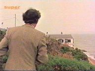 Screenshot (Johnson sieht im Haus von Curton, wie Curton die Insel mit dem Fernglas beobachtet)
